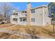 Exterior elevation of the building featuring two balconies, beige siding, and stone chimney accents at 14182 E Colorado Dr # 204, Aurora, CO 80012