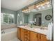 Bathroom with double sink vanity, soaking tub, large mirror, and modern lighting fixtures at 10696 Riverbrook Cir, Highlands Ranch, CO 80126