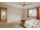 Spacious main bedroom featuring a ceiling fan, window with orange curtains, and neutral walls at 10696 Riverbrook Cir, Highlands Ranch, CO 80126