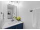 Well-lit powder room featuring a modern vanity with a blue cabinet, elegant mirror, and fresh white towels at 1818 S Quebec Way # 2-3, Denver, CO 80231