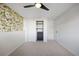 A well-lit bedroom features a closet, floral accent wall, plush carpeting, and a modern ceiling fan at 2700 S Holly St # 100, Denver, CO 80222