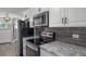 Close up of modern kitchen featuring stainless appliances, backsplash, and solid countertops at 2700 S Holly St # 100, Denver, CO 80222