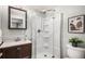 Bright bathroom featuring a corner shower, wood cabinet and a square mirror at 8304 S Upham Way, Littleton, CO 80128
