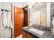 Bathroom featuring decorative stone around mirror and wood cabinetry at 8304 S Upham Way, Littleton, CO 80128