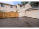 Tan two-story home featuring an attached garage, a wood fence and a paved driveway at 8304 S Upham Way, Littleton, CO 80128