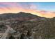 Scenic aerial view of a charming town nestled amidst mountains, with a colorful sky adding to the picturesque setting at 14412 Pansy Loop, Morrison, CO 80465