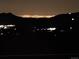 Distant city lights shine through mountains and trees in a captivating night view at 30382 Marys Dr, Conifer, CO 80433