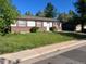 Ranch-style home featuring red shutters, brick accents, and a well-lit front yard with some uncut grass at 5543 Victor St, Denver, CO 80239