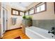 Bright bathroom with decorative windows, soaking tub, and hardwood flooring at 2595 S Adams St, Denver, CO 80210