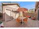 Inviting backyard featuring brick patio, dining set, orange striped umbrella, and a charming weeping tree at 2222 N Washington St, Denver, CO 80205