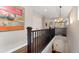 Bright upstairs hallway with a stylish chandelier, wooden railing, and easy access to other rooms at 2222 N Washington St, Denver, CO 80205