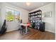 This home office features a bright window, wood floors, minimalist desk and chair, and shelving for storage at 538 S Upham St, Lakewood, CO 80226