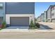 Modern home featuring a gray garage door and manicured landscaping at 6791 Navajo Ct, Denver, CO 80221