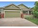 Charming green home featuring a two-car garage and brick accents at 1851 S Marshall Cir, Lakewood, CO 80232