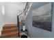 Elegant staircase with wooden steps, black iron railings, and decorative artwork at 3800 Umatilla St, Denver, CO 80211
