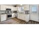 Bright and modern kitchen features white cabinetry, stainless steel appliances and wood-look flooring at 13072 Westlake Pl, Broomfield, CO 80020