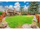 Large grassy backyard featuring mature trees, stone landscaping and a wooden fence perimeter at 7583 S Xanthia Ct, Centennial, CO 80112