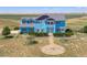 Two-story light blue house with landscaping and a long driveway at 8441 Flint Ridge St, Bennett, CO 80102