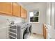 Bright laundry room featuring a modern washer and dryer, ample storage, and a sunlit window at 17826 E Cloudberry Dr, Parker, CO 80134