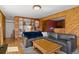 Comfortable living room featuring wood-paneled walls, hardwood floors, and an open layout leading to the adjacent kitchen at 27231 Log Trl, Conifer, CO 80433