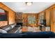 Inviting living room featuring wood-paneled walls, a stone fireplace, comfortable seating, and scenic views through the windows at 27231 Log Trl, Conifer, CO 80433
