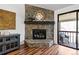 Living room with stone fireplace, hardwood floors, and access to outdoor balcony at 7770 W 87Th Dr # F, Arvada, CO 80005