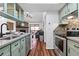 Modern kitchen with green cabinets and stainless steel appliances with view to living room and fireplace at 7770 W 87Th Dr # F, Arvada, CO 80005