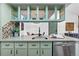Kitchen with green cabinets, stainless steel appliances, and open shelving showing view to dining area at 7770 W 87Th Dr # F, Arvada, CO 80005