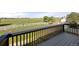 A gray deck with black railings overlooks a vast, green pasture and white-fenced field at 1788 Shoshone Trl, Elizabeth, CO 80107