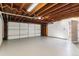 Spacious garage with exposed wood beams, a white door, painted floors, and a door to the exterior at 625 S Xenon Ct, Lakewood, CO 80228