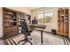 Well-lit home office featuring built-in bookshelves, a modern desk, and a large window with neighborhood views at 21855 E Idyllwilde Dr, Parker, CO 80138