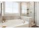 Well-lit bathroom featuring a soaking tub, glass-enclosed shower, and neutral tile at 6041 N Orleans St, Aurora, CO 80019