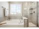 Bathroom view showcasing a soaking tub, glass shower and modern neutral tile at 6041 N Orleans St, Aurora, CO 80019