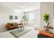 Bright living room featuring a brown leather sofa, green rug and plants for a cozy and inviting space at 6041 N Orleans St, Aurora, CO 80019