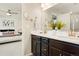 A modern bathroom with double sinks, dark wood cabinetry and a view into the bright bedroom at 6041 N Orleans St, Aurora, CO 80019
