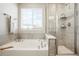 Bright bathroom featuring a soaking tub next to a glass enclosed shower with shelving and tiled walls at 6041 N Orleans St, Aurora, CO 80019