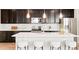 Well-equipped kitchen with dark cabinets, a herringbone backsplash, and a large island with counter seating at 6041 N Orleans St, Aurora, CO 80019