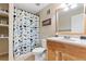 Well-lit bathroom featuring a wood vanity, patterned shower curtain, and built-in shelving at 1825 Cooper Ct, Castle Rock, CO 80109