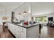 Open kitchen and living space features a large kitchen island, stainless appliances, and hardwood floors at 7605 E Windlawn Way, Parker, CO 80134