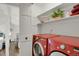 Convenient laundry room with modern red washer and dryer, open shelving, and ample space for laundry tasks at 7605 E Windlawn Way, Parker, CO 80134