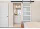 Bedroom featuring a sliding barn door leading to a bright bathroom with modern vanity at 10088 E 62Nd Ave, Denver, CO 80238