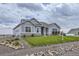 Gray siding ranch home with stone accents and a well-manicured lawn at 16122 Emporia Way, Brighton, CO 80602