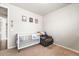 Neutral-toned bedroom features a white crib, cozy armchair and charming baseball-themed decor at 2404 Horse Shoe Cir, Fort Lupton, CO 80621