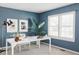 A bright home office featuring a blue accent wall, modern furnishings, and ample natural light from a nearby window at 674 Huntington Dr, Highlands Ranch, CO 80126