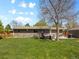 Expansive backyard with manicured lawn, hot tub, mature tree, fire pit, and back of home at 4779 S Owens Way, Littleton, CO 80127