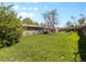 Lush green backyard featuring a hot tub, large lawn, mature trees, and the rear exterior of the home at 4779 S Owens Way, Littleton, CO 80127