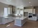 Well-appointed kitchen featuring white cabinetry, a center island, modern appliances, and plenty of counter space at 16655 W 93Rd Pl, Arvada, CO 80007