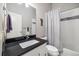 Modern bathroom features sleek black countertops, recessed lighting, and gray decor at 1857 W 67Th Pl, Denver, CO 80221