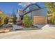 Well-maintained exterior featuring a tan garage door, neat landscaping, and a blue exterior at 1857 W 67Th Pl, Denver, CO 80221