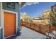 Inviting front porch with a vibrant orange door, wooden fence, and beautiful landscaping at 1857 W 67Th Pl, Denver, CO 80221